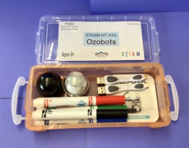 Picture of an Ozobot STEAM Kit with two Ozobots, four coloured markers, and two charging cables visible within the container.
